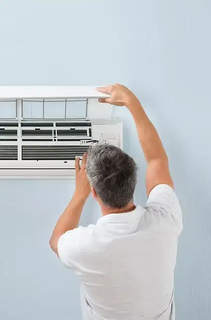 Technician removing the cover of a wall-mounted AC for deep cleaning and disinfection — Greenwave service.